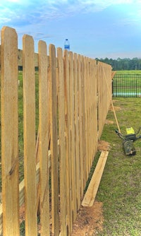 a wooden fence is being built in a grassy area